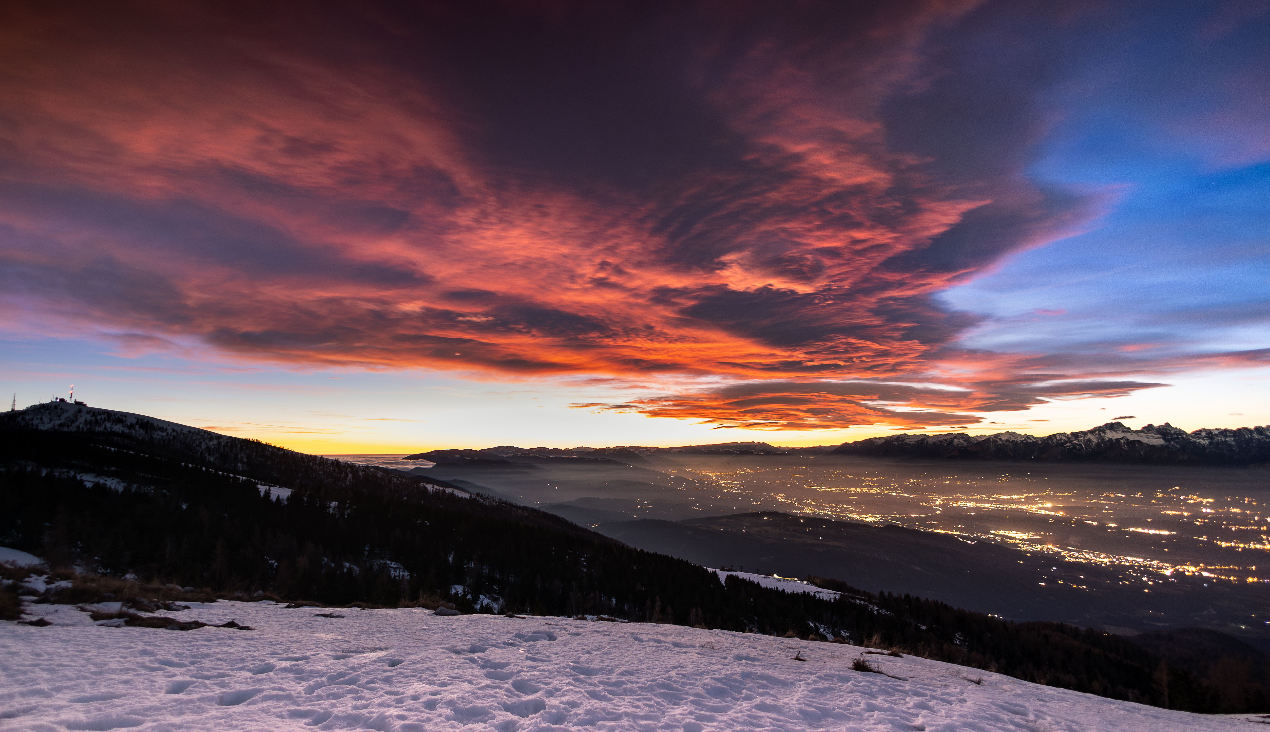Capture of a breathtaking alpine sunset, featuring glowing clouds and snow-covered mountains under a vibrant sky.