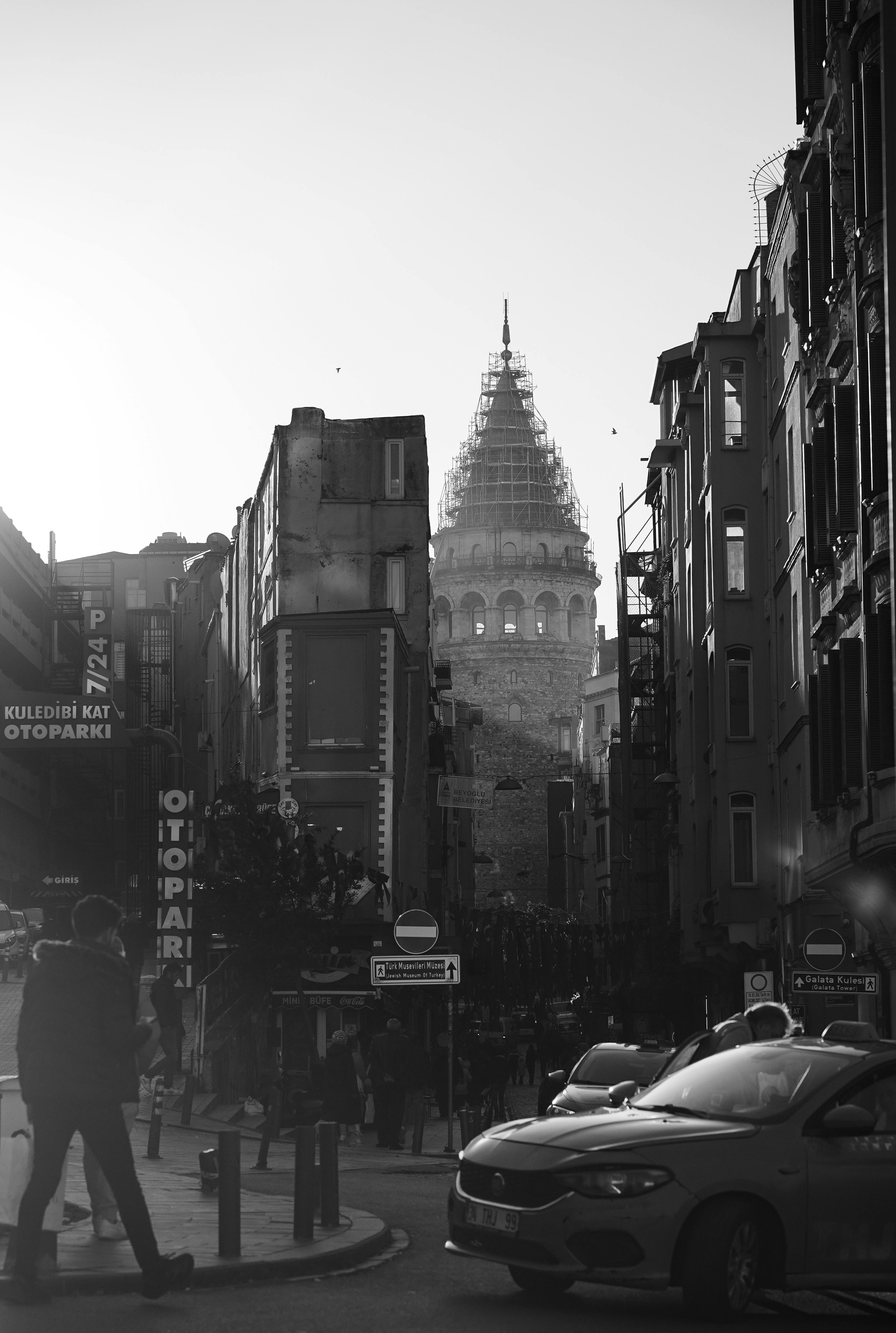 Monochrome street view featuring the iconic Galata Tower amidst urban life in Istanbul.