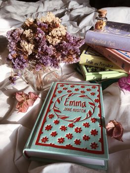 Books and dried flowers create a cozy, literary atmosphere in a serene bedroom setting.