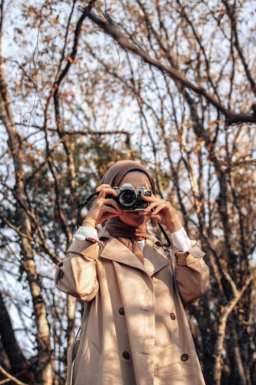 Woman Wearing Coat Taking a Picture in a Forest in Fall