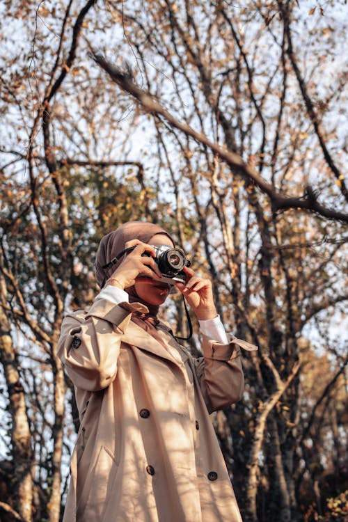 Woman Wearing Coat Taking a Picture in a Forest in Fall