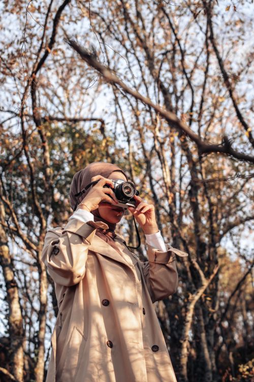 Woman in a coat photographing a fall forest