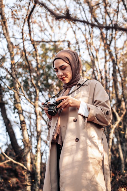 Woman Wearing Coat Taking a Picture in a Forest in Fall