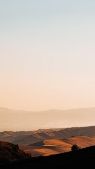 Peaceful evening landscape with soft sunset light over arid hills and expansive sky.