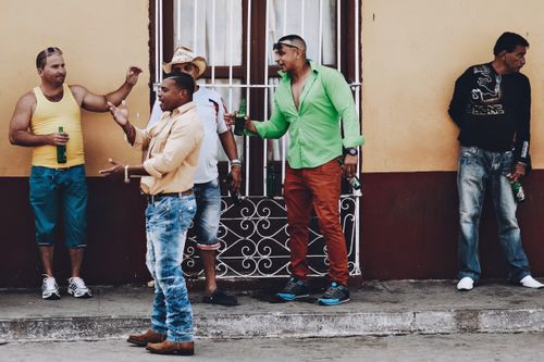 Free Group of men socializing with drinks on a city street in a vibrant urban neighborhood. Stock Photo