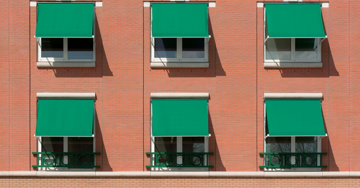 Exterior view of a brick apartment building with green awnings.