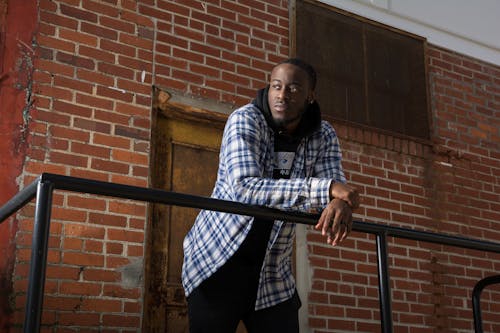 Man in Hoodie Sweatshirt and Check Shirt Leaning on Railing