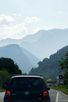 SUV traveling through scenic mountain road surrounded by lush forests.