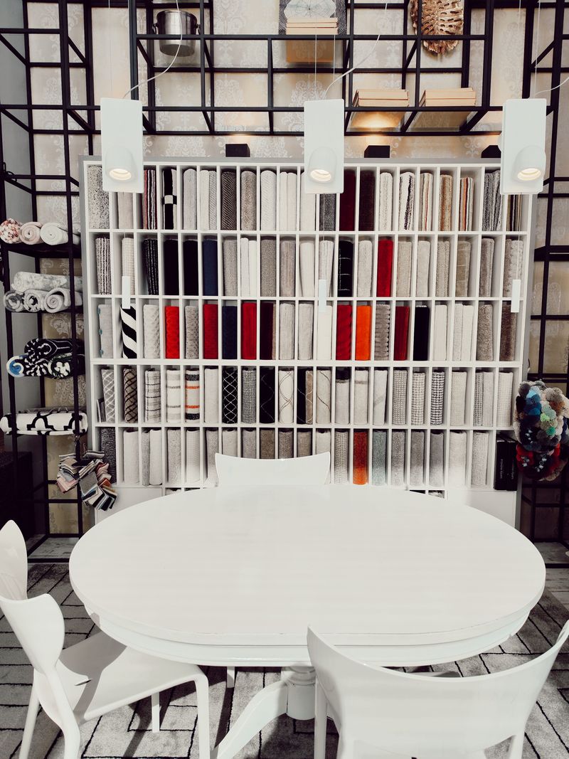 A showroom wall of material and textile samples above a round table — photo by tiago alves on Pexels