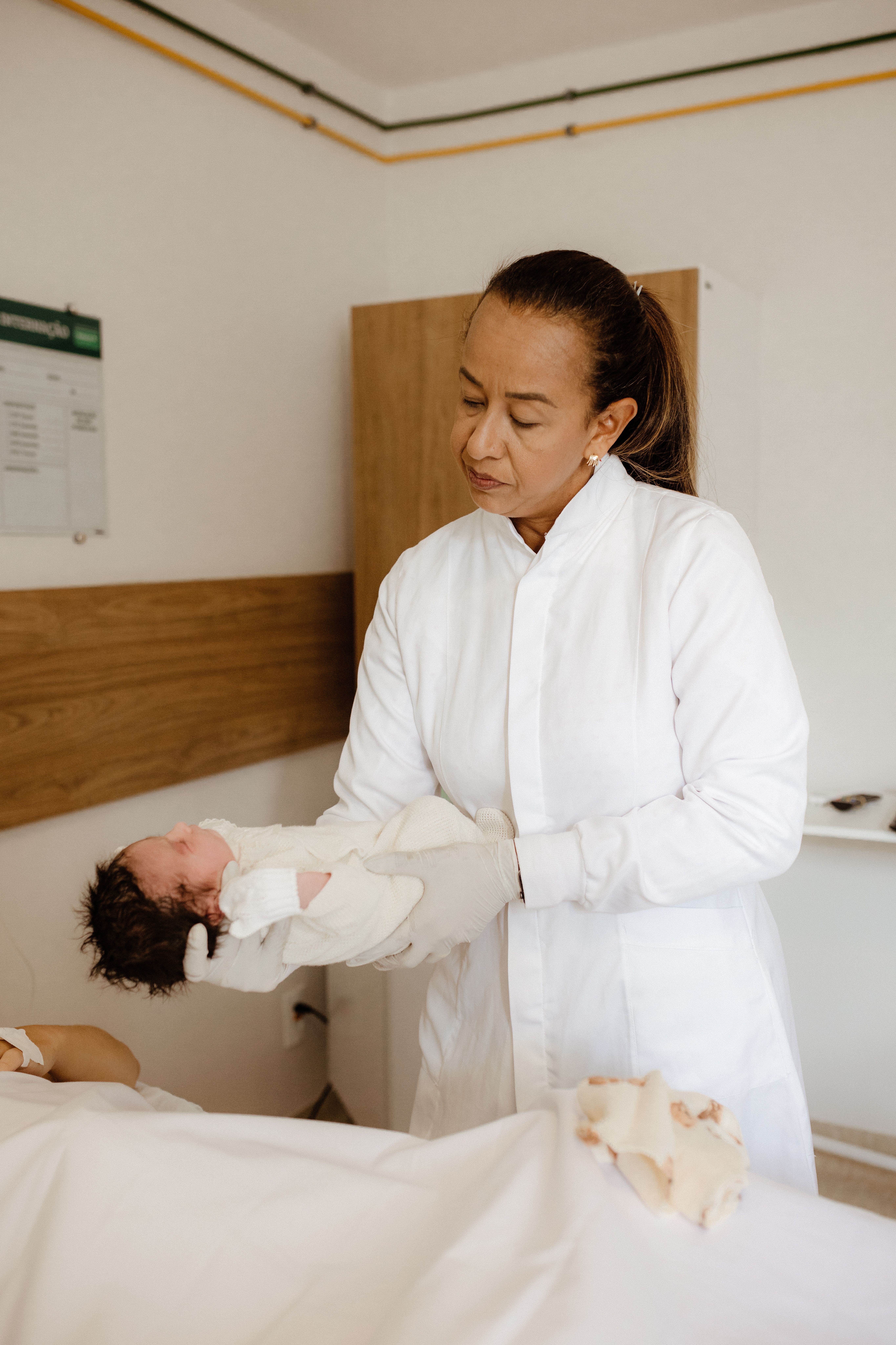 A doctor in a white coat cradling a newborn baby in a hospital setting.