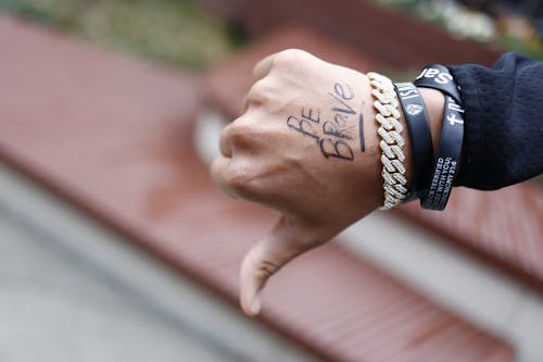 Tattooed Hand Wearing Rubber Bands Showing Thumb Down Gesture