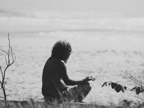 A solitary man smokes by the beach, captured in a striking black and white silhouette.