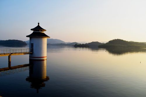 Free Serene lake scene with a tower and scenic reflections at sunrise, perfect for travel and nature themes. Stock Photo