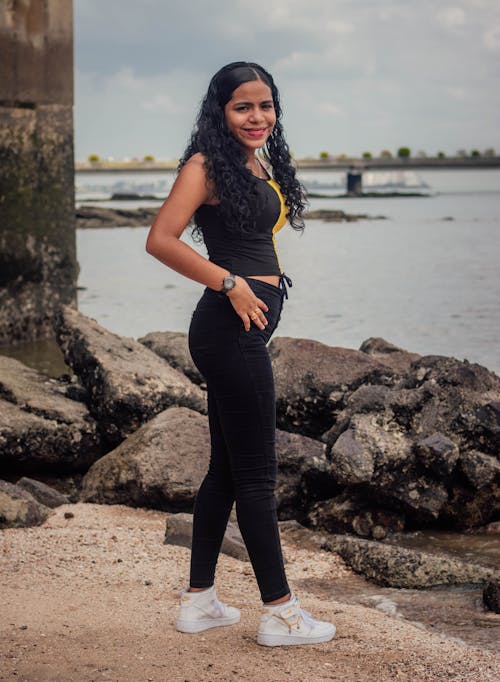 Woman in Running Clothes Standing on Rocky River Bank