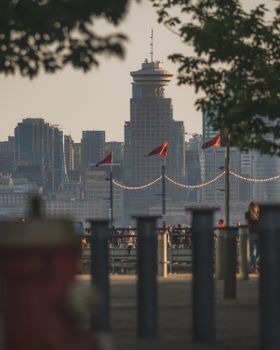 Scenic view of Vancouver skyline with iconic Canada Place framed by trees at sunset.