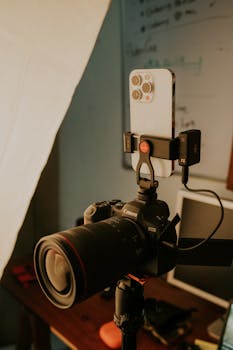 Close-up of a smartphone mounted on a professional DSLR camera, showcasing modern photography technology.