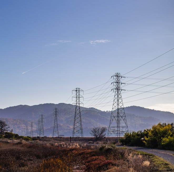 Serene countryside landscape showcasing mountains and electrical poles under a clear blue sky.