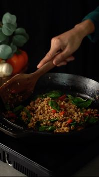 Close-up of a vibrant stir-fry in a skillet being stirred with fresh greens and vegetables.