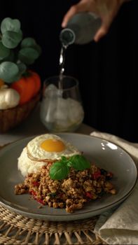 A savory breakfast dish featuring a fried egg, minced meat, and fresh basil garnished elegantly on a plate.