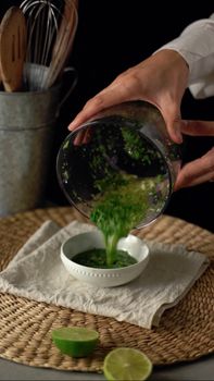Fresh herb sauce being poured into a bowl, perfect for adding a flavorful touch to dishes.