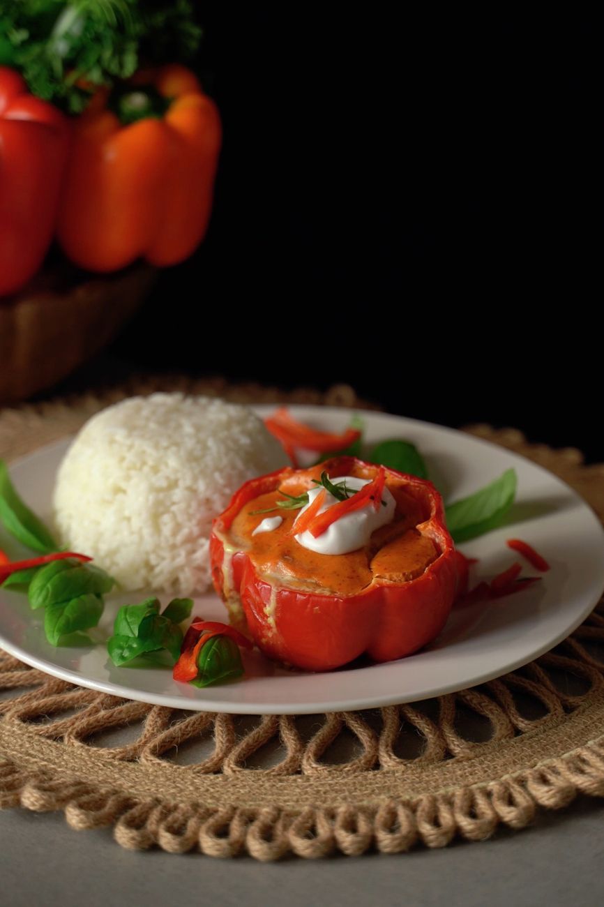Red rocoto peppers stuffed with seasoned meat and cheese, golden from baking, served on a white plate with rice, showing the deceptive appearance of this intensely spicy Peruvian dish