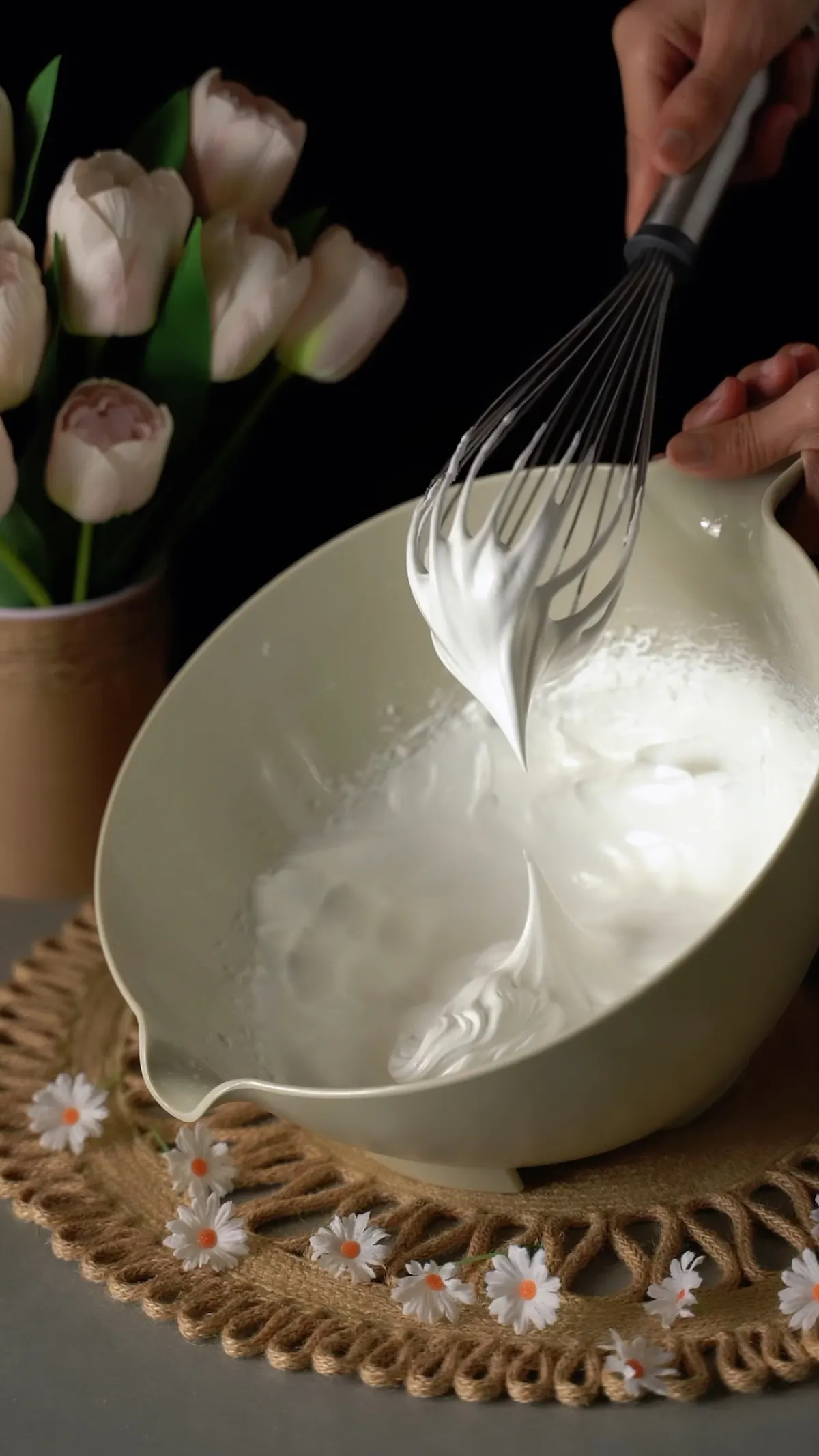 Tangan mengocok whipped cream dengan whisk di mangkuk untuk dessert layering
