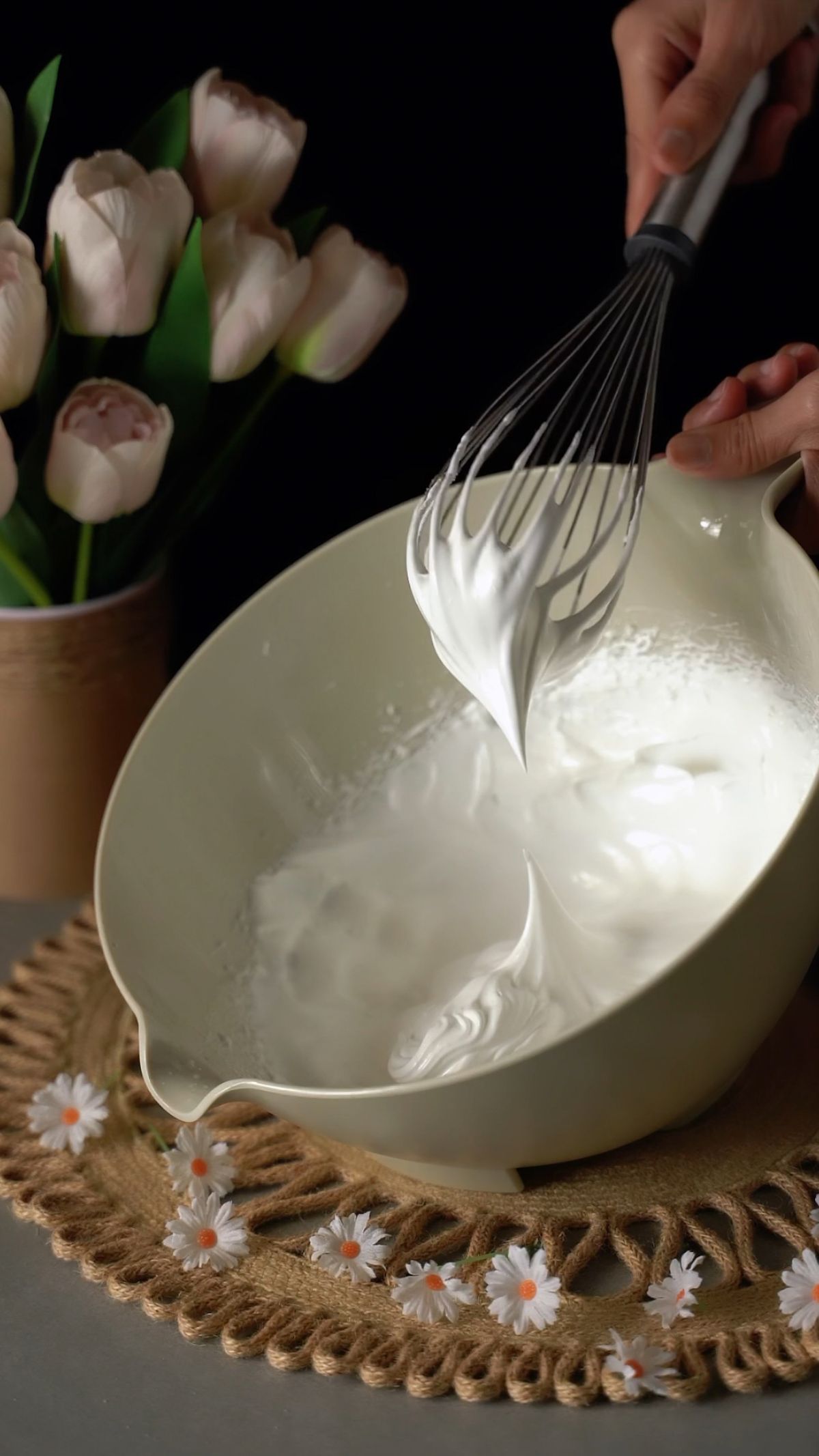 Tangan mengocok whipped cream dengan whisk di mangkuk untuk dessert layering
