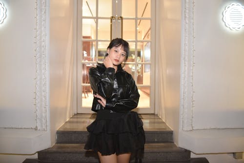 Model in a Short Leather Jacket and a Black Mini Skirt Front of the Restaurant Entrance