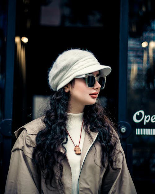 Young Woman in a White Cap and a Beige Jacket Leaving a Cafe