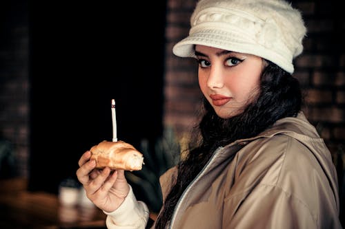 Woman in Hat Holding Food with Burning Candle