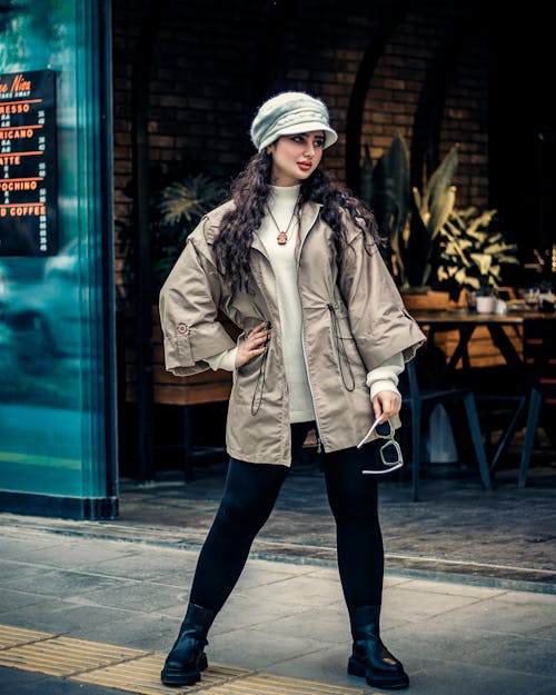 Model in a Beige Jacket over a White Sweater and Black Leggings in Front of a Restaurant