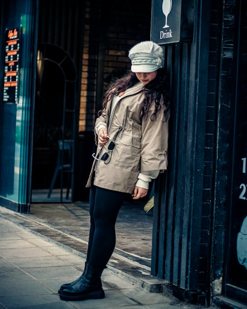 Woman in Jacket and Hat Leaning on Wall