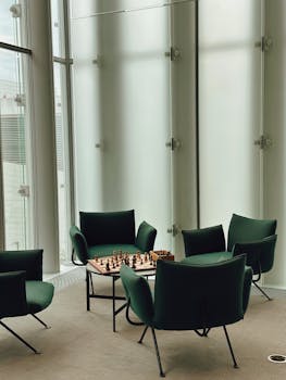 Contemporary lobby featuring a chessboard on a coffee table surrounded by green armchairs.