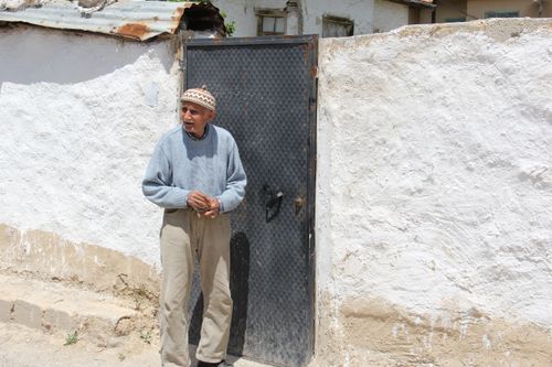 Free Senior man standing by a wall, reflecting a rustic rural lifestyle. Stock Photo