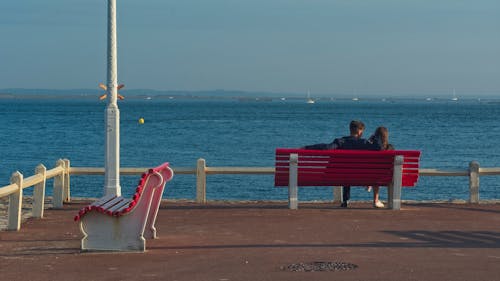 Young Couple Sitting on a Bench on the Sea Promenade