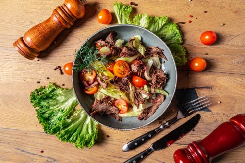 Free A vibrant grilled meat salad with fresh vegetables and herbs on a wooden table. Stock Photo