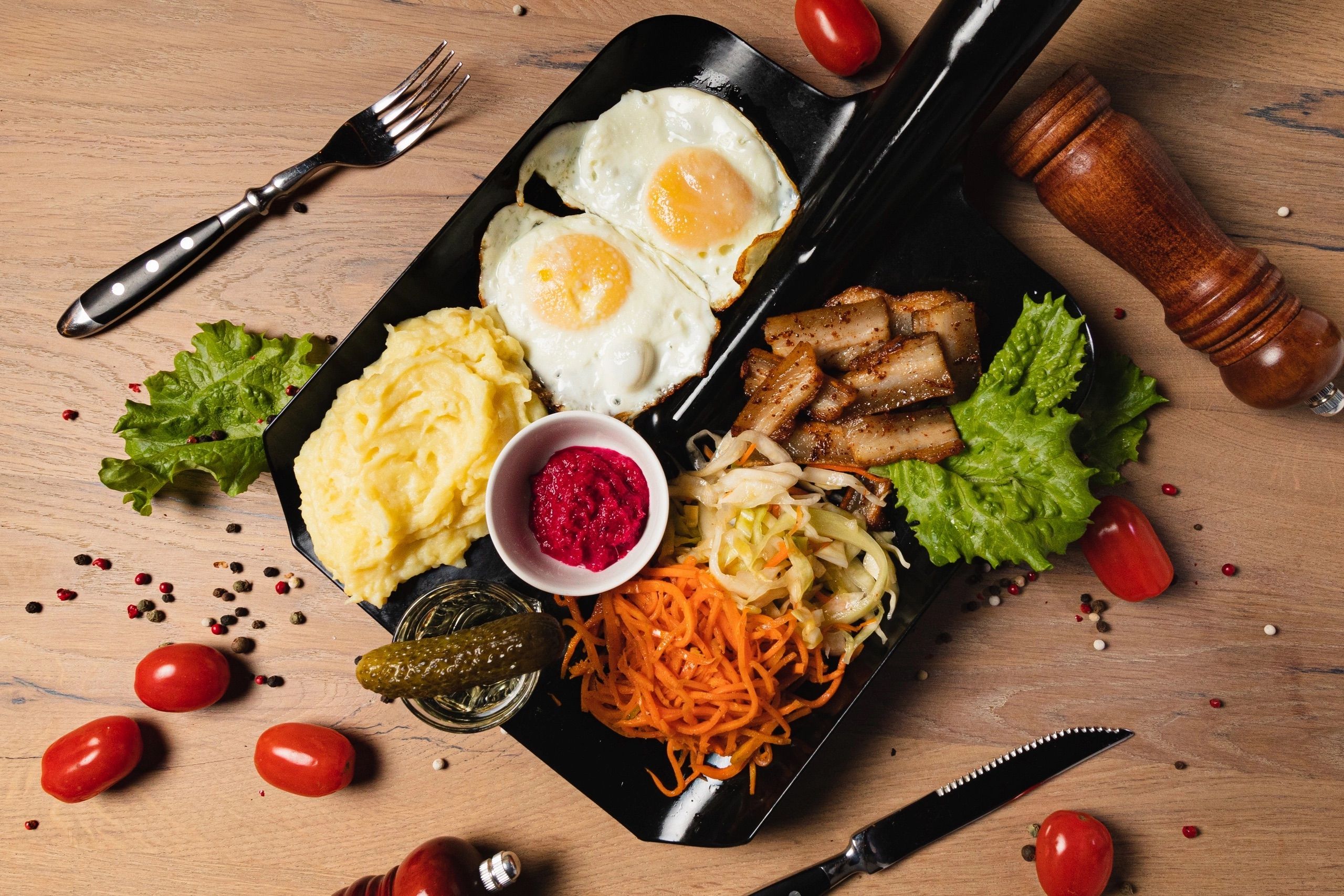 A vibrant top-down view of a gourmet platter featuring fried eggs, vegetables, and sides on a wooden table.
