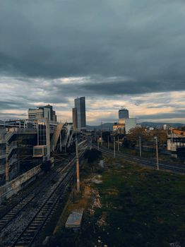Moody cityscape view of İzmir with railroad tracks and modern architecture at dusk.