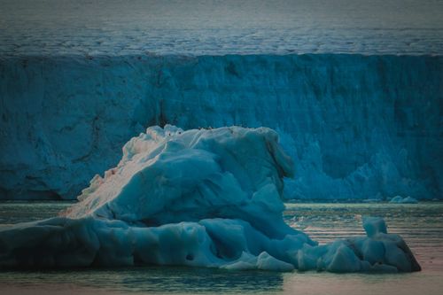 Free Dramatic view of an iceberg in the Arctic sea against a vast glacier during twilight. Stock Photo