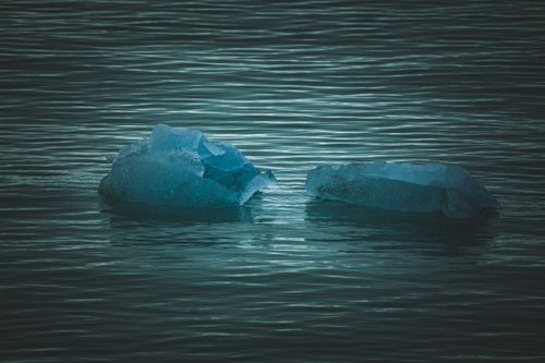 Free Two ice chunks floating on a calm sea, creating a serene and cold atmosphere. Stock Photo