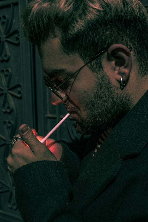Free Elegant man in coat lights cigarette outdoors at night in Edirne, Türkiye. Stock Photo
