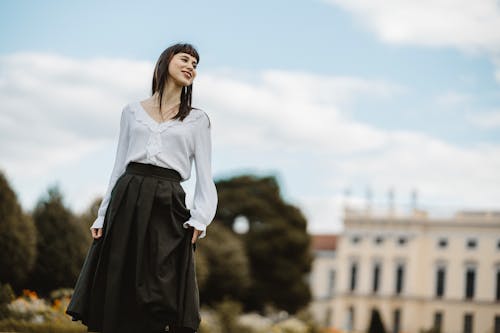 Model in a White V-Neck Retro-Style Blouse and a Pleated Skirt