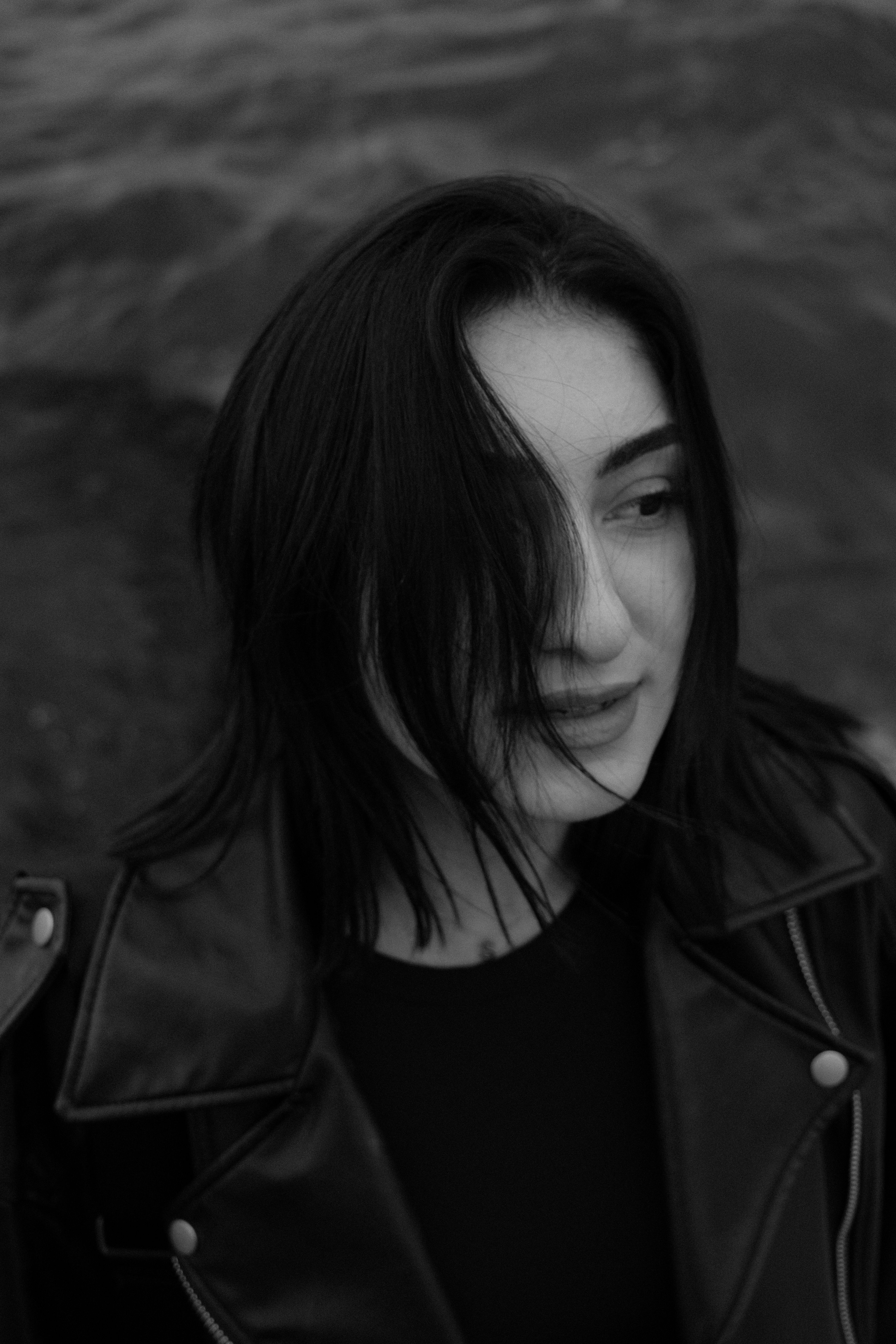 Artistic black and white portrait of a woman wearing a leather jacket outdoors.