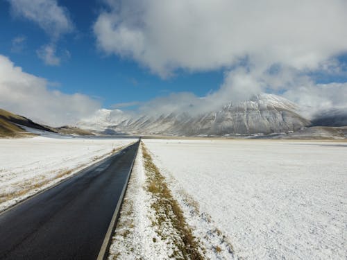 Empty Road on Plains in Snow with Mountain behind