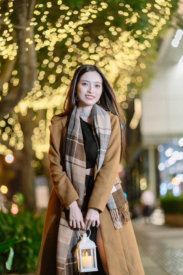 Woman in wool coat with lantern and Christmas lights