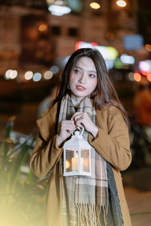 Young Woman Standing Outside in City and Holding a Lantern 