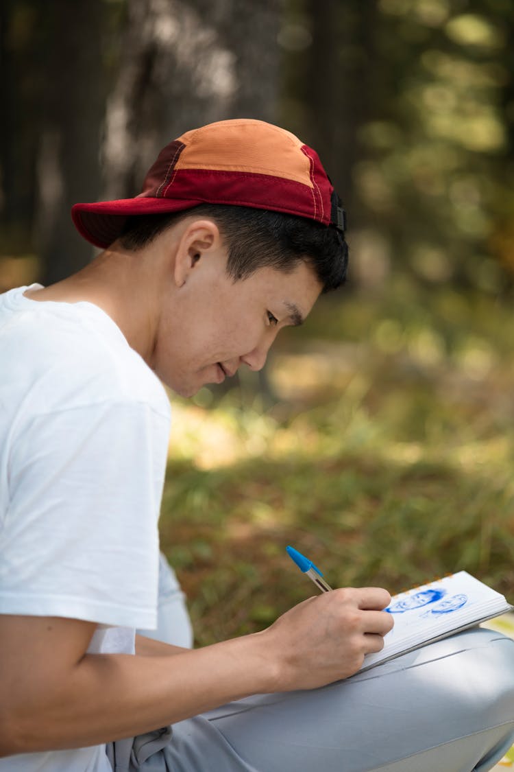 Young Man Sitting Outside And Drawing 