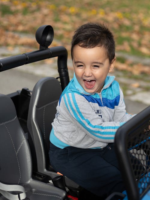 Smiling Boy Sitting in Toy Car