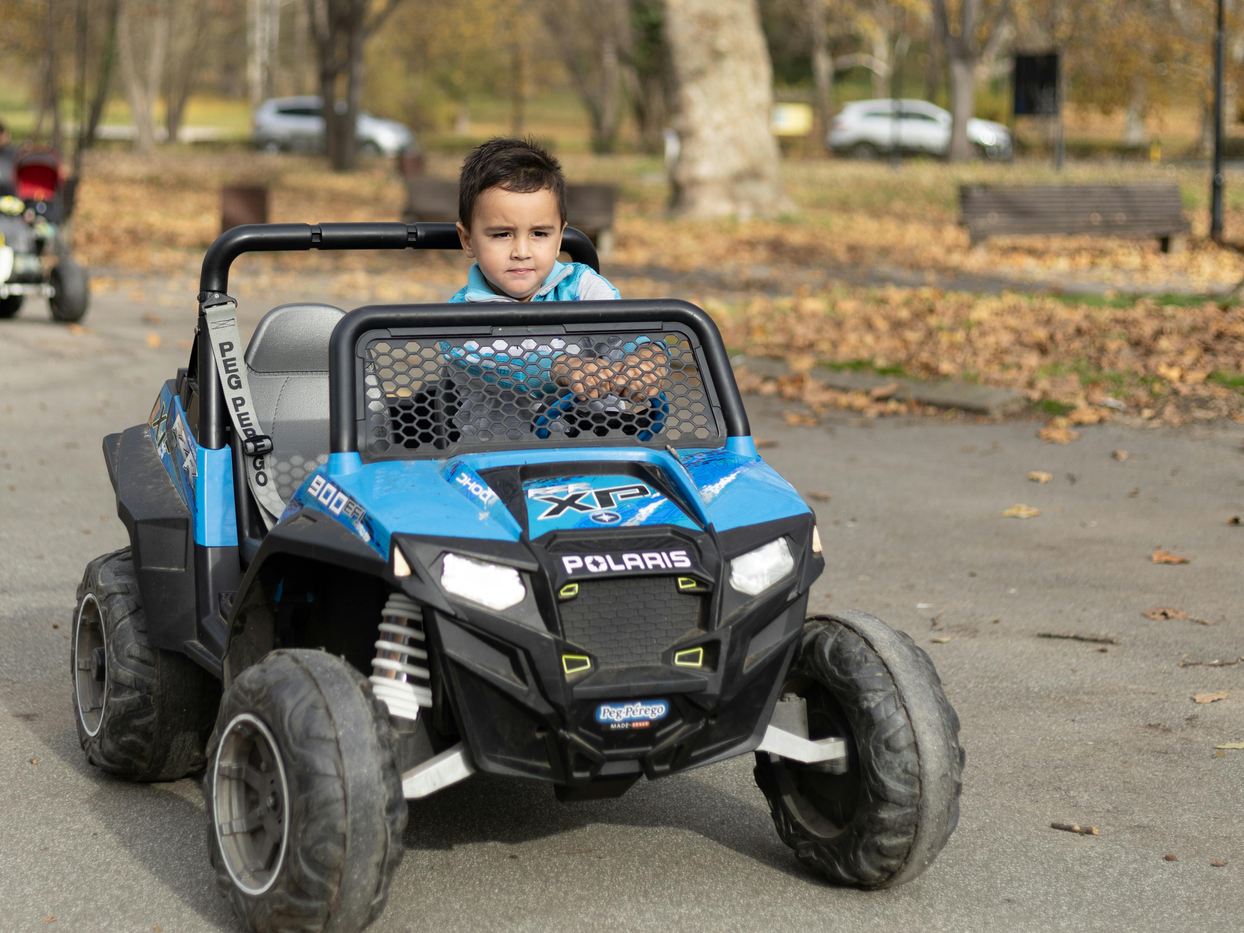 Kids Ride-On Toys Battery Powered: Safe Fun for 2025 12 A young boy riding a blue electric toy quad bike on a sunny day in the park.
