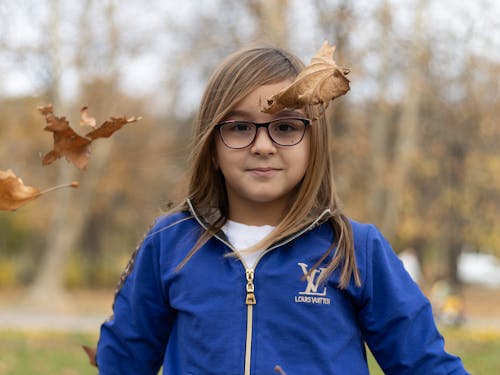Free Small Girl with Eyeglasses Wearing a Louis Vuitton Tracksuit Standing in the Park Stock Photo